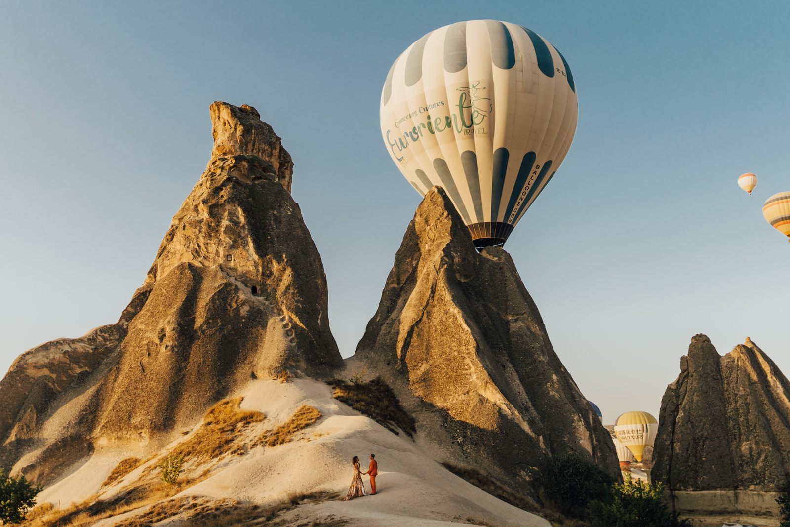 bride and groom walking up mountain in cappadocia with hot air balloon behind them