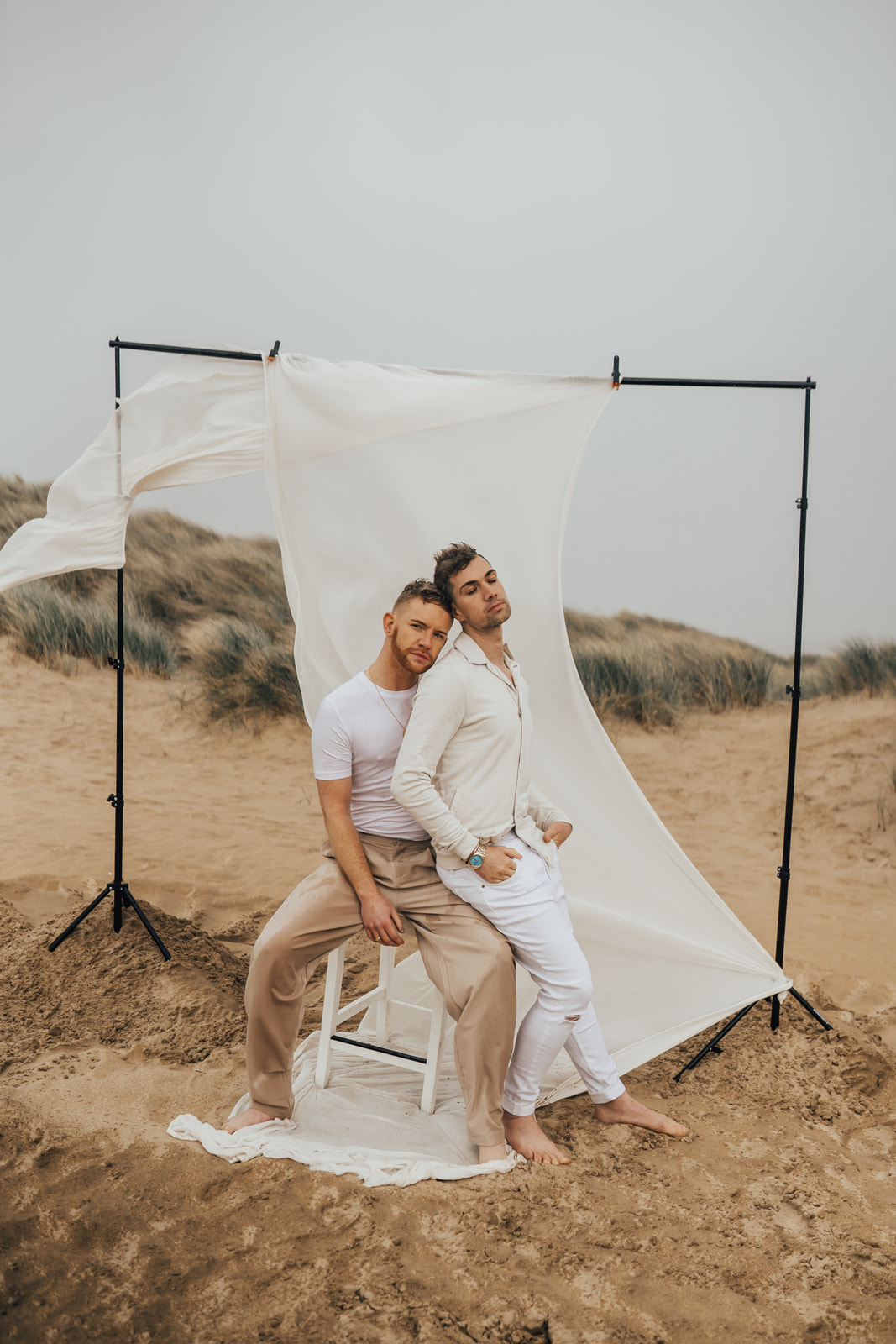 two grooms on the beach with fabric installation