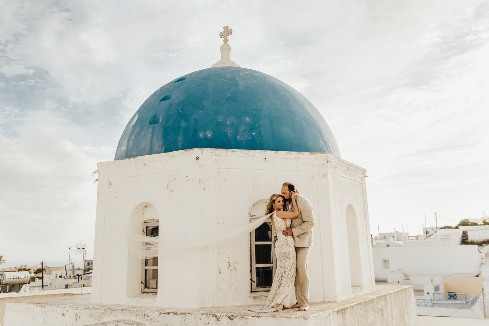 Bride and groom on white roof top blue dome in Santorini
