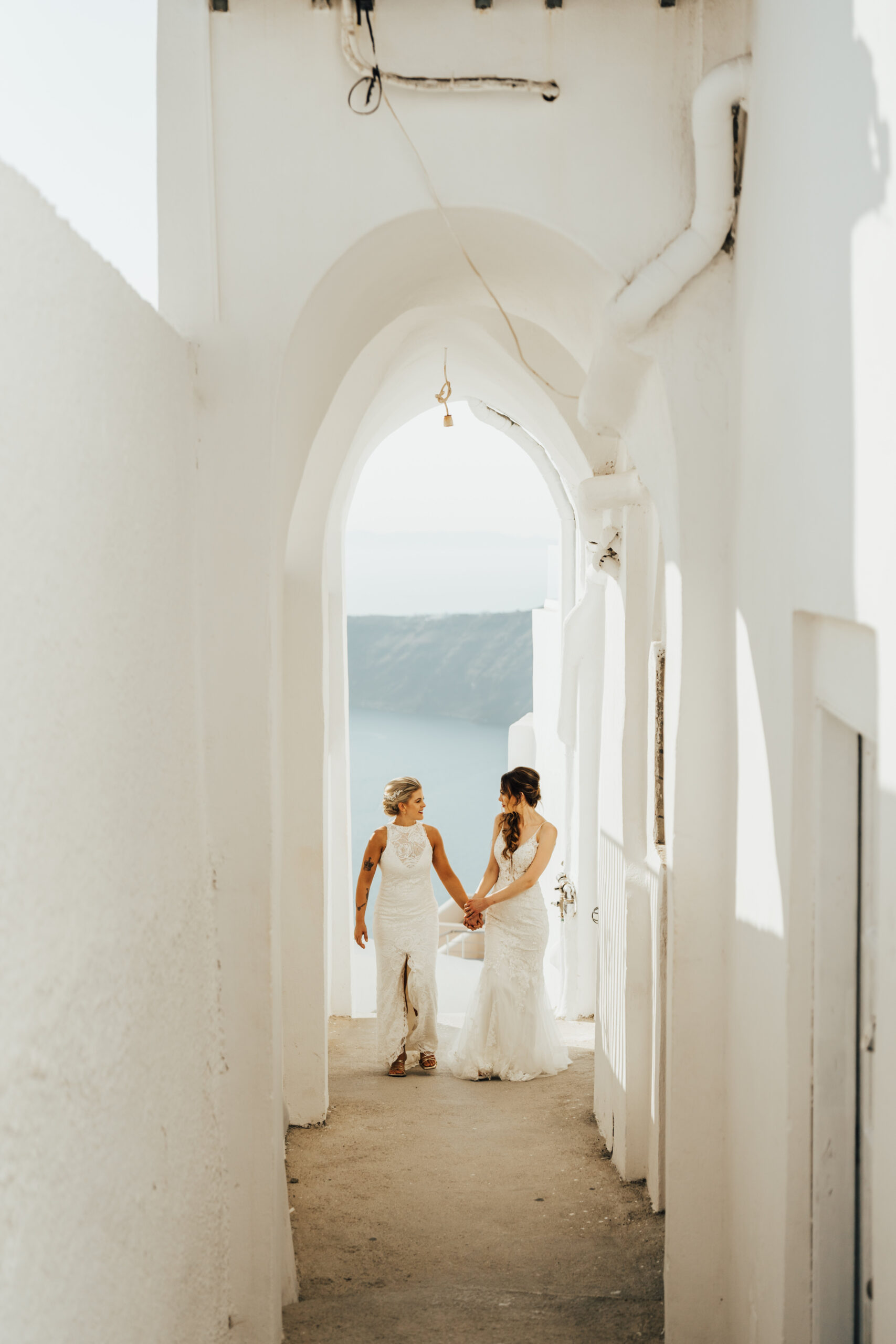 Two brides walking holding hands in Santorini