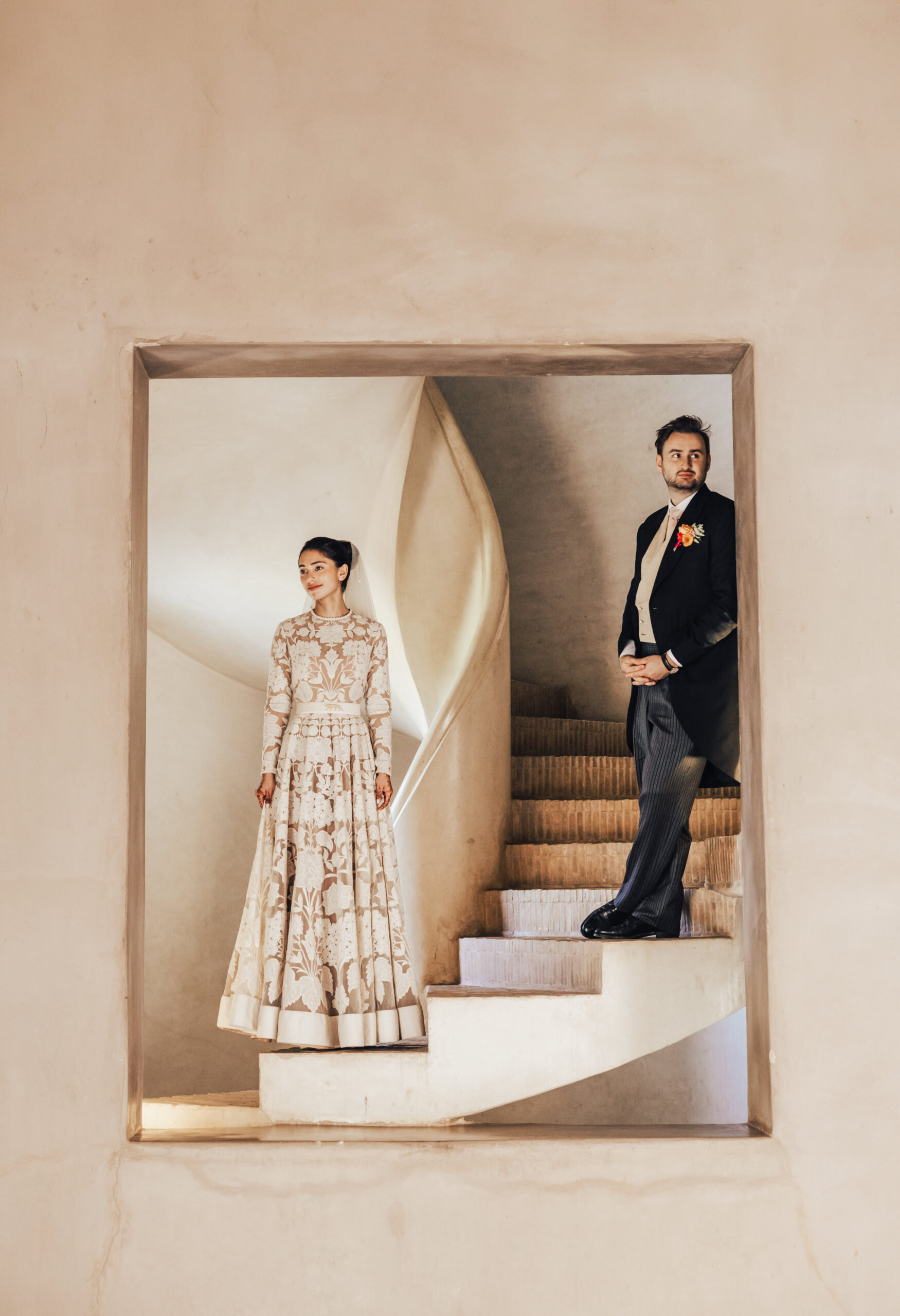 Bride and groom standing on staircase frame opening in Ksar Char-Bagh wedding venue, Marrakech