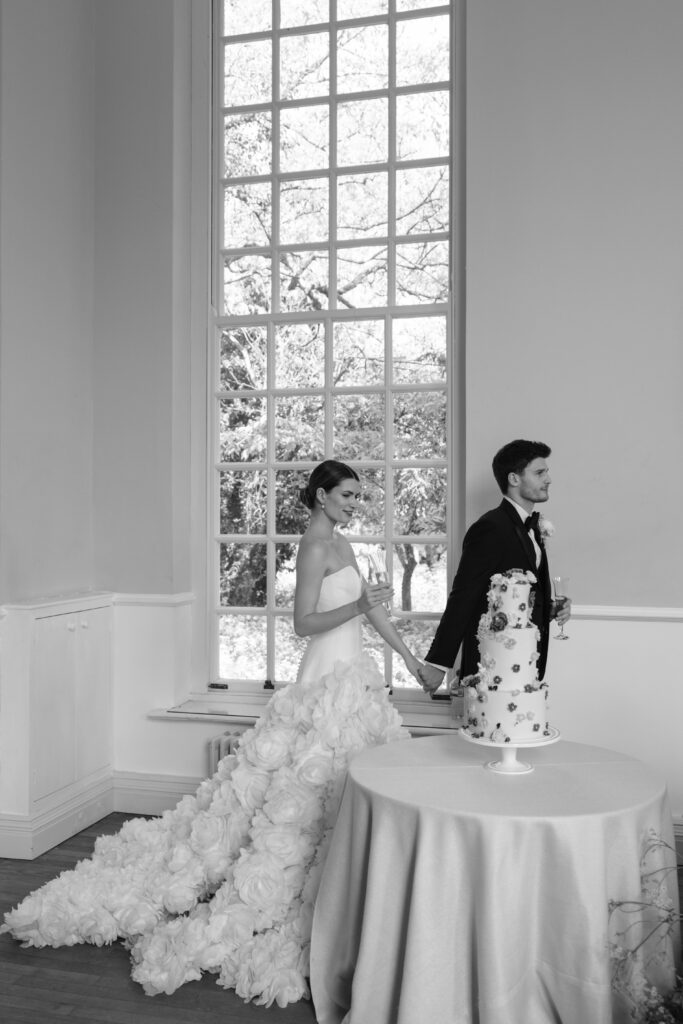 photo of bride and groom walking past wedding cake