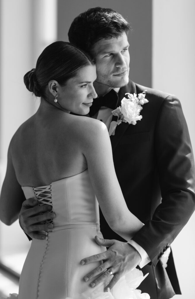 bride and groom cuddling looking out of window