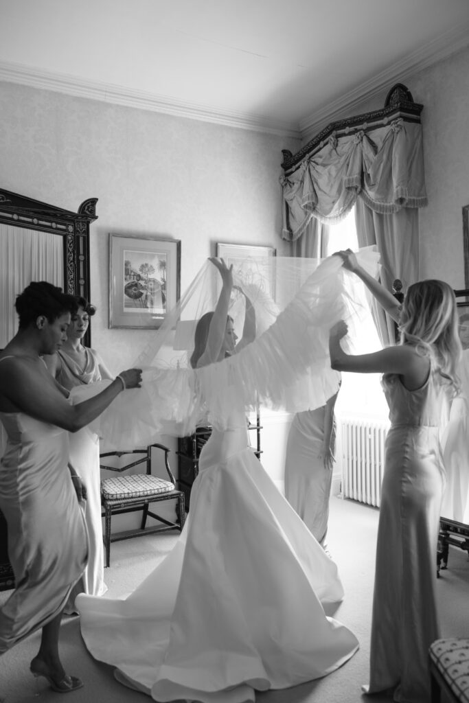 bride and bridesmaids helping bride getting wedding veil on