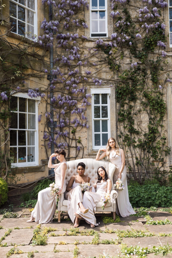 bridesmaids sitting on couch outside house with wisteria