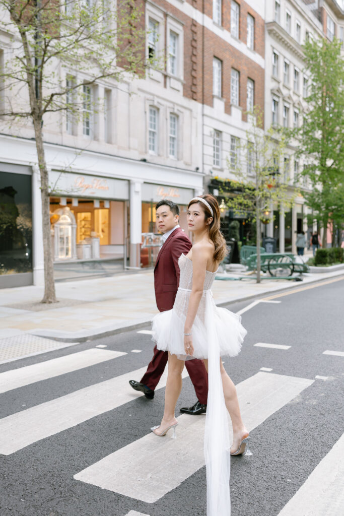 bride and groom holding hands walking across zebra crossing