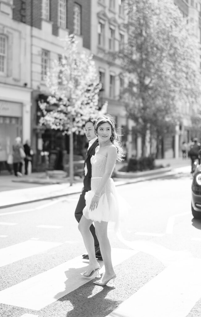bride and groom holding hands walking across zebra crossing