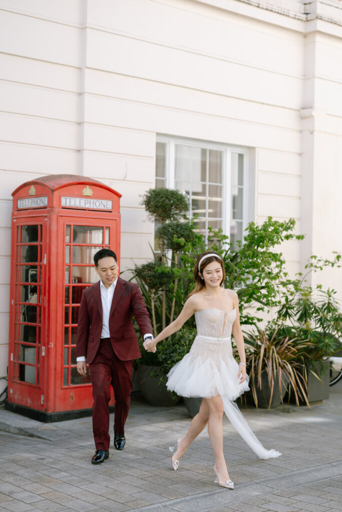 london pre wedding shoot bride and groom walking infront of red phone box