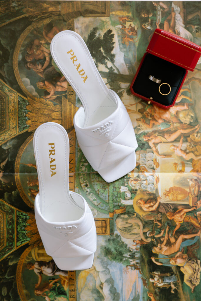 prada sandals on top of book and cartier rings