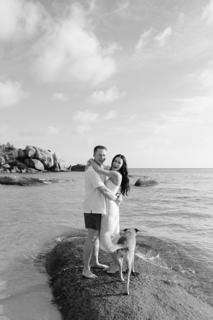 A man and woman posing for a picture on a beach.