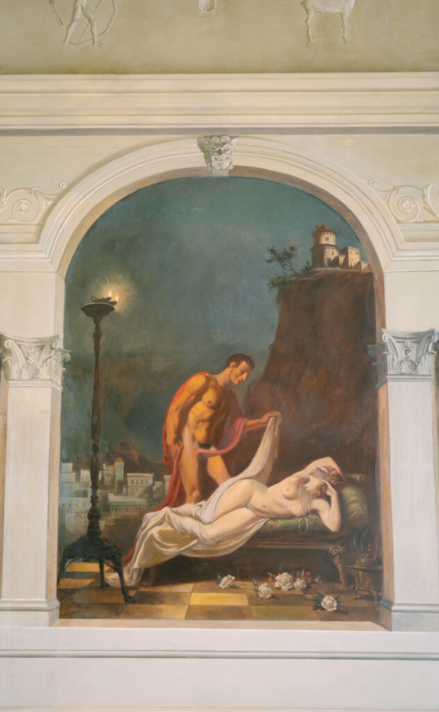 A classical-style painting of a muscular man in a red cloak gently uncovering a reclining nude woman on a bed, set against a dramatic landscape with a cliff, buildings, and a burning torch nearby.